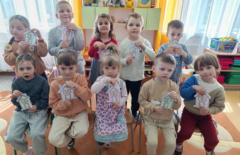 Зображено дітей, які тримають в руках  паперові будиночки