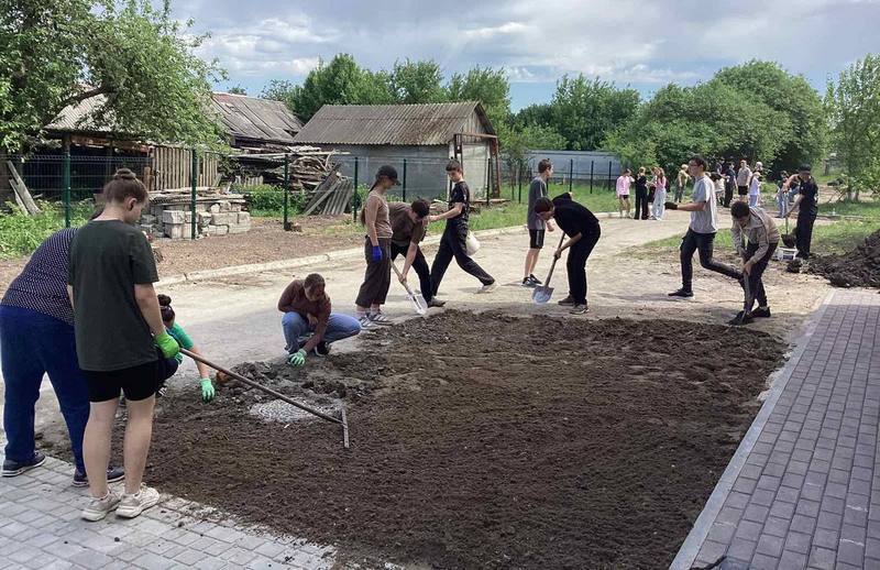 Учні прибирають клумби на території школи