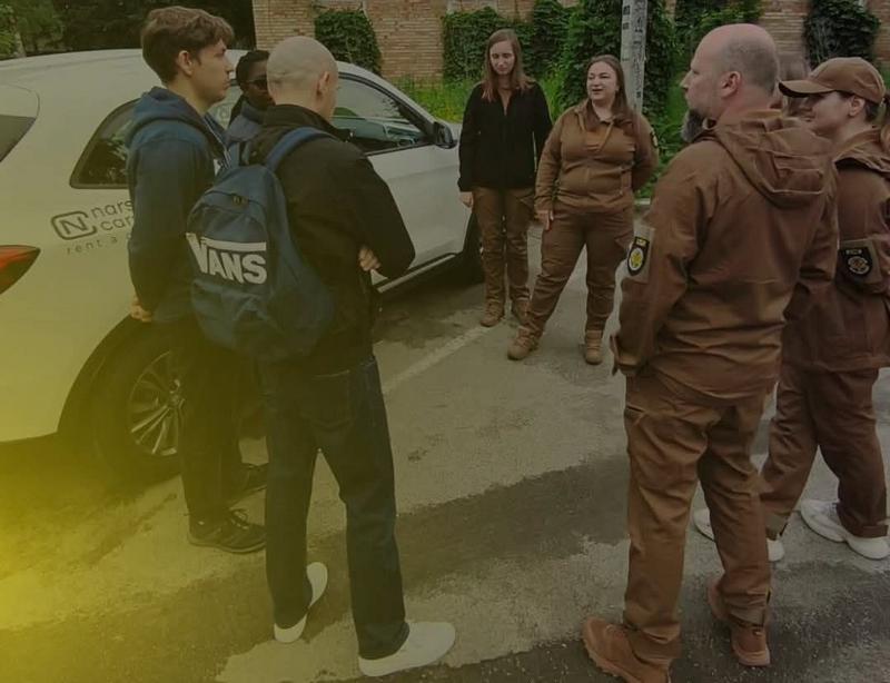 Представники міжнародної делегації та саперки Асоціації саперів України спілкуються на парковці