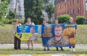 Рідні захисників тримають великі банери з портретами військовослужбовців. Ліворуч — Литвинчук Дмитро, праворуч — Світельський Олександр, із написом «Віримо, чекаємо вдома!»
