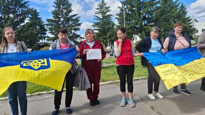 Жінки та чоловік на акції пам'яті та підтримки тримають Державний Прапор України та саморобні плакати із закликами повернути їхніх рідних із полону