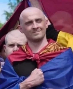 Звільнений із російського полону захисник України Євген Крикливий, обгорнутий у синьо-жовтий прапор.