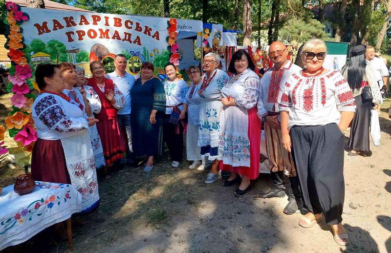 Учасники обласного фестивалю, вдягнені у вишиванки та традиційні українські костюми, посміхаються та спілкуються біля святкової локації.