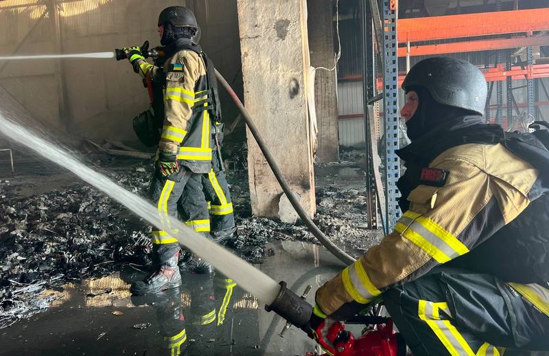 Двоє рятувальників спільно гасять пожежу в зруйнованому складському приміщенні