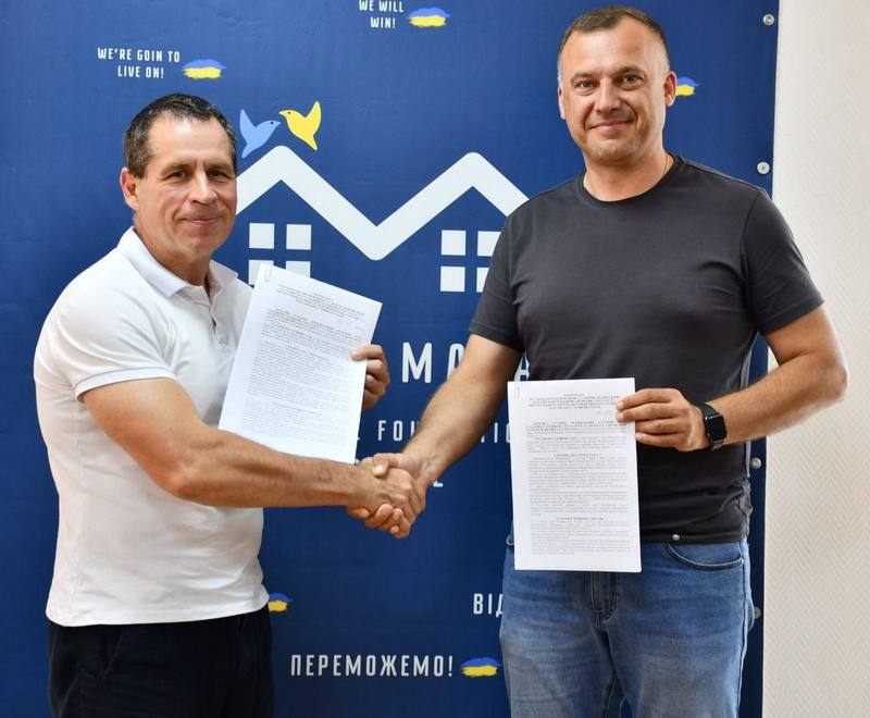 Урочисте рукостискання Вадима Токара та представника медичного центру на тлі банера після підписання Меморандуму