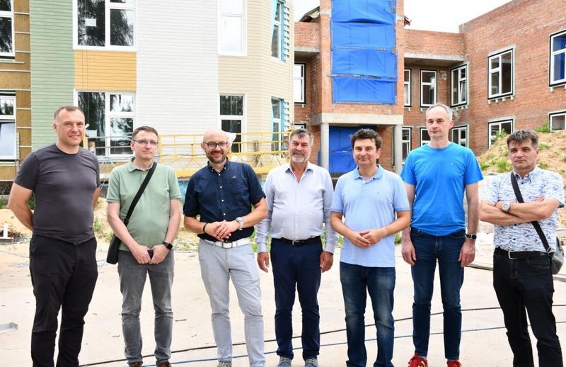 Учасники навчального візиту з Польщі та представники місцевої влади на тлі будівлі закладу освіти Макарова, що перебуває на стадії будівництва.