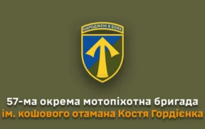 Зображення військового шеврона 57 ОМПБр. На щиті синьо-зеленого кольору зображено золотий наконечник стріли (спис). Угорі на жовтій стрічці напис 'НАРОДЖЕНІ В БОЯХ'. Під шевроном текст: '57-ма окрема мотопіхотна бригада ім. кошового отамана Костя Гордієнка'.