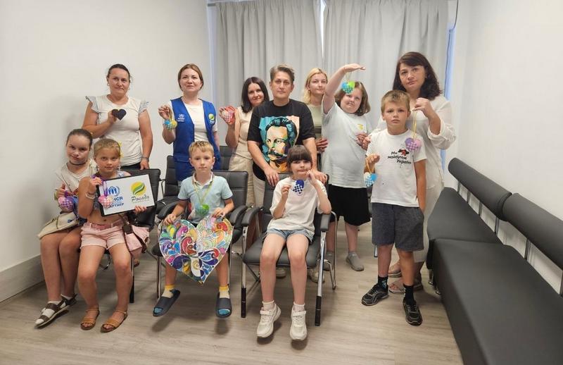 Спільне групове фото дітей та дорослих із фетровими серцями в руках у Ветеранському просторі «Серед Своїх» після завершення психологічного тренінгу.