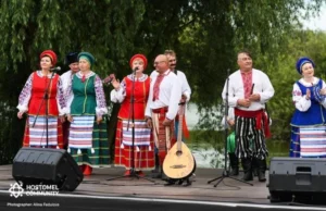 Учасники ансамблю «Чебреці» у вишиванках та сценічному вбранні співають на сцені біля річки, представляючи Макарівську громаду на культурному заході.