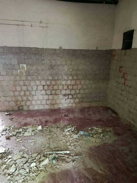 Стіна харчоблоку з відбитою штукатуркою, видно цегляну кладку та будівельне сміття на підлозі. Початок ремонту.