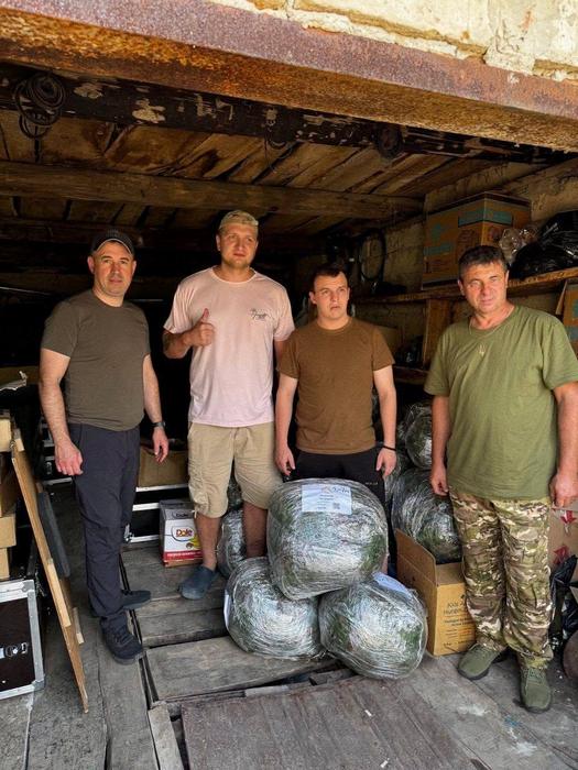 Представники Макарівської громади, волонтери та військові стоять поруч із переданими маскувальними сітками та гуманітарним вантажем.