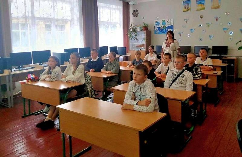 Учні у вишиванках сидять за партами в комп'ютерному класі під час першого уроку