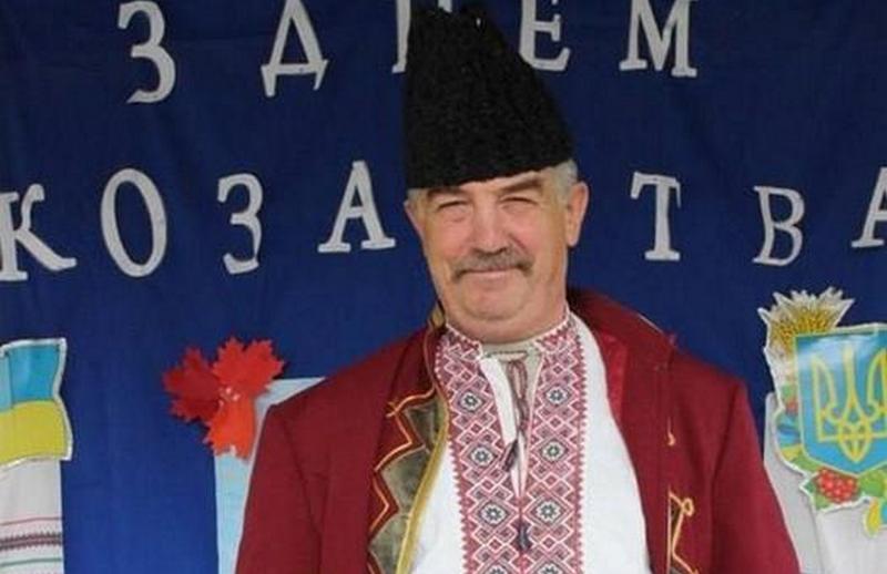 Олег Валентинович Сич у вишиванці, жупані та високій козацькій шапці на тлі святкового банера до Дня козацтва.