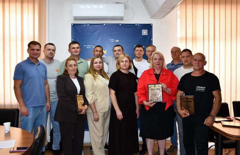 Групове фото учасників урочистого нагородження з нагоди Дня фізичної культури і спорту в Макарівській громаді. На фото: заступник селищного голови Лариса Омельченко, директор ФСК «Макарівська громада» Олександр Богдюк та нагороджені тренери і вчителі фізкультури з дипломами в руках.