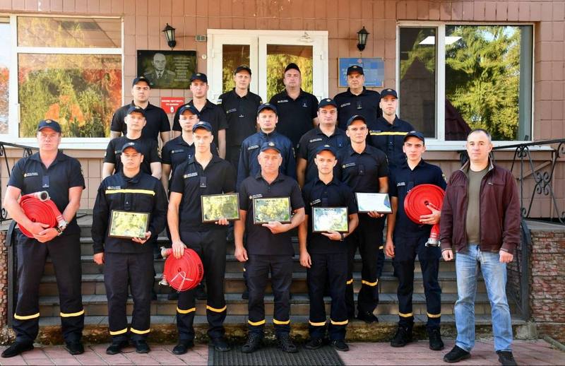 Колективне фото рятувальників ДСНС та Юрія Сірцова на сходах підрозділу. Вогнеборці тримають у руках вручені грамоти й згорнуті пожежні рукави.