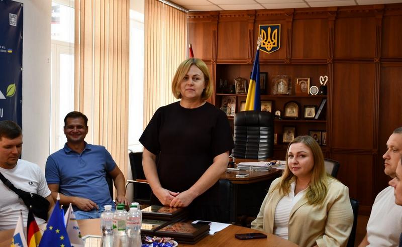 Керівництво Макарівської селищної ради на зустрічі зі спортсменами та тренерами. У центрі стоїть заступник селищного голови Лариса Омельченко. На столі підготовлені почесні дипломи.