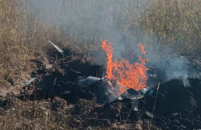 Палаючі уламки збитого безпілотника у землі.