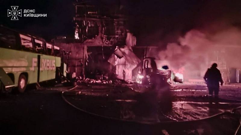 Ліквідація пожежі підрозділами ДСНС після влучання БПЛА в селі Копилів: палаюча будівля СТО, пошкоджені автобус FlixBus і вантажівка, силает рятувальника на тлі диму.