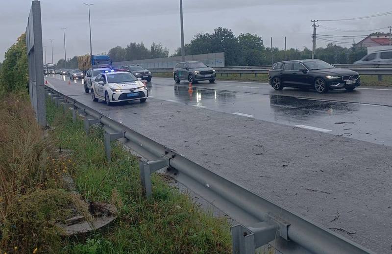 Поліцейський автомобіль з увімкненими проблисковими маячками регулює рух на мокрій автодорозі Київ — Чоп у районі села Березівка після ворожого обстрілу.