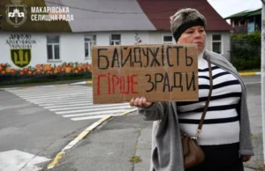 Жінка тримає картонний плакат із написом від руки «Байдужість гірше зради» під час мирної акції.