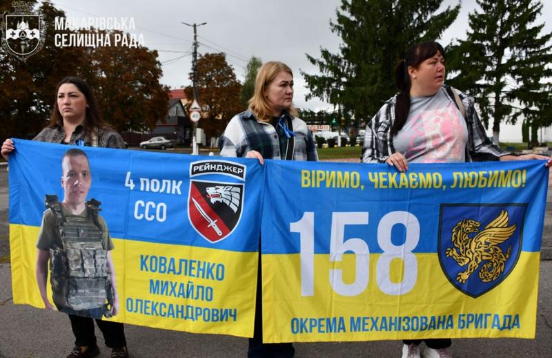 Жінки тримають плакати-прапори з фотографіями військовослужбовців (Коваленко Михайло Олександрович, 4 полк ССО та 158 окрема механізована бригада) із написом «Віримо, чекаємо, любимо!».