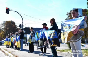 Рідні військовослужбовців стоять уздовж вулиці, тримаючи в руках банери з фотографіями та іменами полонених і зниклих безвісти захисників.