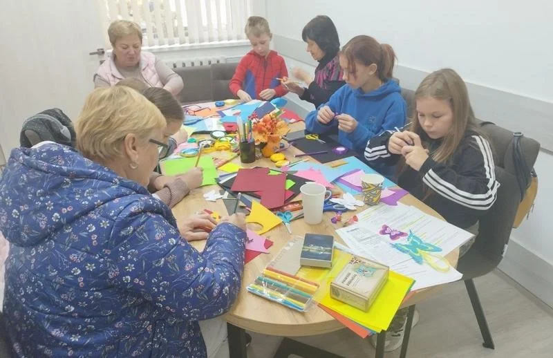Діти та дорослі за столом під час творчого майстер-класу у ветеранському просторі.